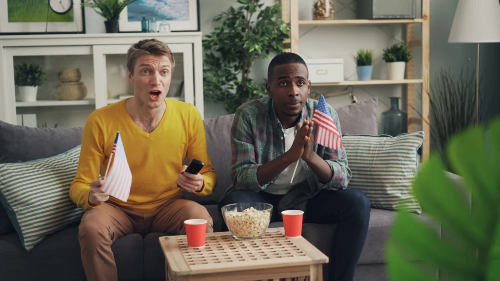Best IPTV Service in the USA: The Complete Guide Friends watching IPTV together at home in the USA, holding a small American flag